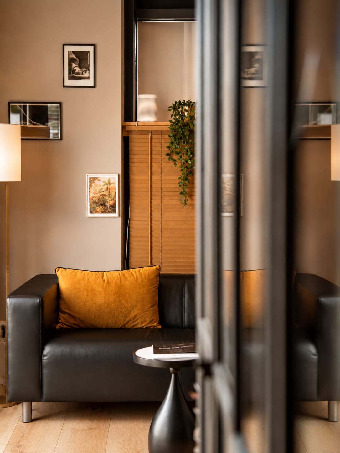 Le salon des Bains d'Hygie, aperçu à travers la verrière — canapé et coussins safran